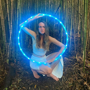 Woman with blue LED hula hoop in bamboo forest