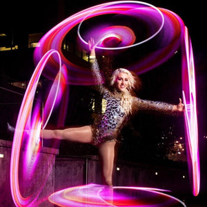 Woman with glowing hula hoops performing at night
