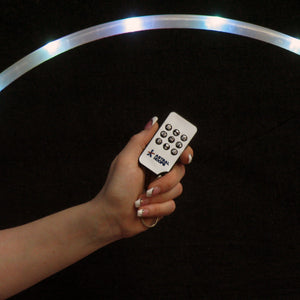 Hand holding remote control near illuminated hoop.
