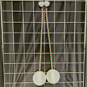 Two white poi balls hanging on grid.