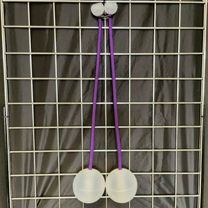 Two white poi balls with purple cords hanging on a grid.