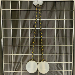 Two white poi balls hanging from a black and gold cord.