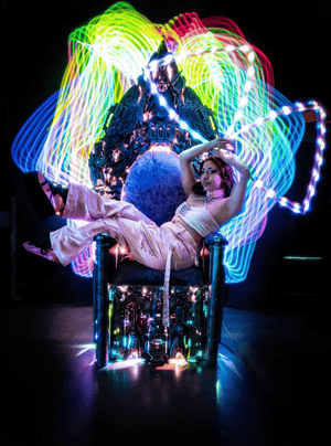 Woman in pink on throne with rainbow light art, Feb 14 screenshot.