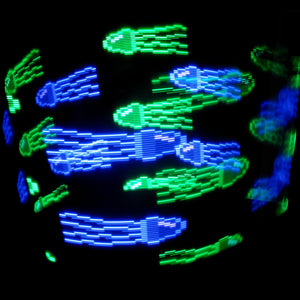 Glowing blue and green pixel jellyfish in the dark.