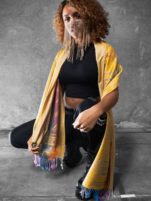 Woman wearing yellow dharma shawl, mask, & black outfit